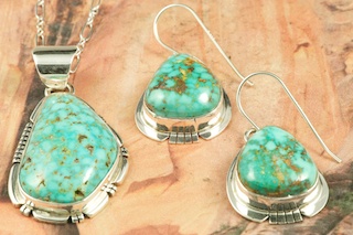 Genuine High Grade Kingman Web Turquoise set in Sterling Silver. Beautiful Pendant and Earrings Set. Created by Navajo Artists Kathy Yazzie and Phillip Sanchez. Signed by the artist. The Mineral Park Mine, in the Cerbat Mountains 14 miles northwest of Kingman, was first mined by Indians centuries before white man came to the area. It is one of the three sites of prehistoric mining localities in the state of Arizona. Mineral Park was the most extensively worked area by the Indians of the three. S.A. �Chuck� Colbaugh found a cache of stone hammers uncovered in ancient trenches and tunnels, when he had the turquoise mining concession in May of 1962. Ithaca Peak and Turquoise Mine (formally called Aztec Mountain or Aztec Peak) are the most famous of the peaks in the area containing turquoise.